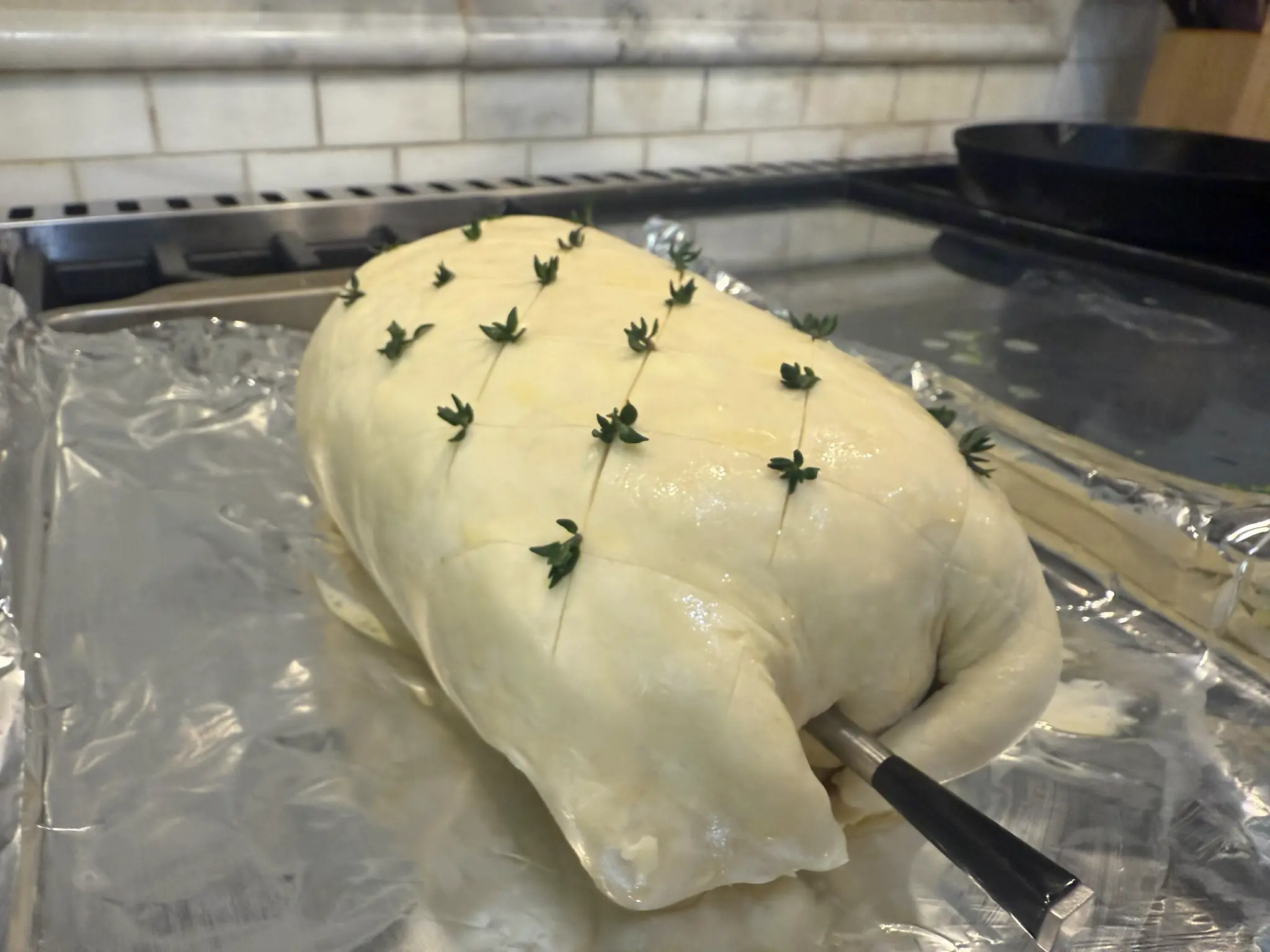 Beef Wellington preparation with herb garnish