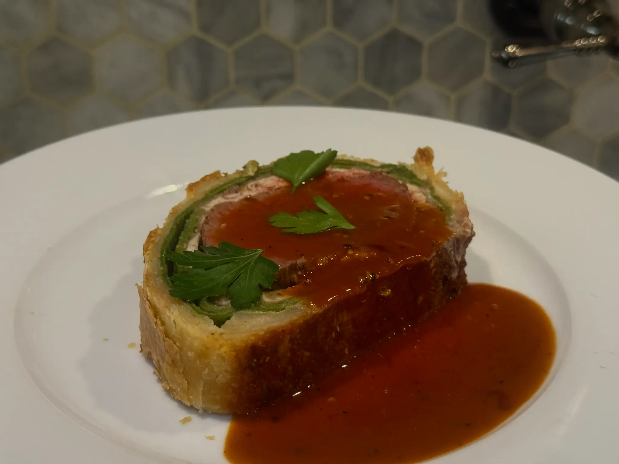 Beef Wellington plated with rich demi-glace sauce
